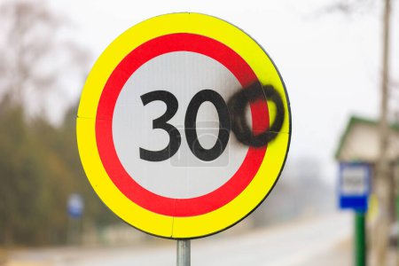 Téléchargez les photos : Les vandales ont peint le chiffre zéro sur un panneau routier avec une limite de vitesse de 30 kilomètres à l'heure. 300 kilomètres par heure panneau arrière-plan - en image libre de droit