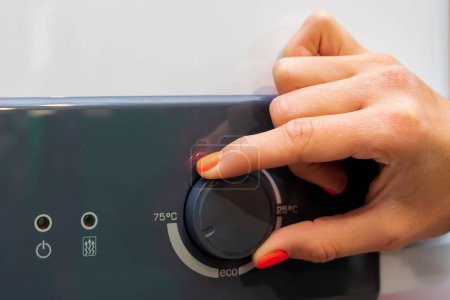Finger auf das Thermostat eines neuen Heizkessels. Hintergrund mit selektivem Fokus und Kopierraum für Text
