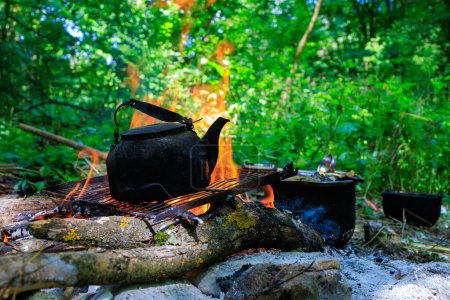 Kettle on campfire. Camping or hiking. Background with selective focus and copy space