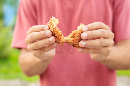 La mano de un hombre sostiene una pastelería dulce con mermelada, merienda y concepto de comida rápida. Enfoque selectivo en manos con fondo borroso y espacio de copia para texto.