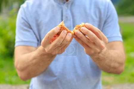 A man's hand holds a sweet pastry with jam, snack and fast food concept. Selective focus on hands with blurred background and copy space for text.