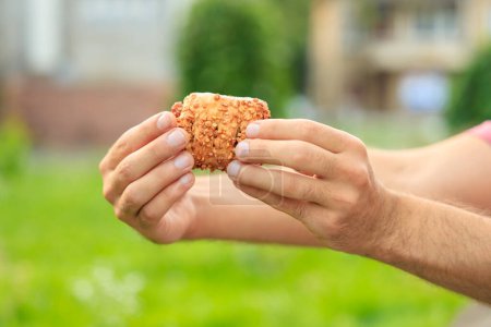 Photo for A guy's hand holds a sweet pastry with jam, snack and fast food concept. Selective focus on hands with blurred background and copy space for text. - Royalty Free Image