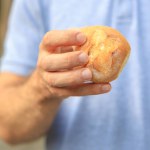 Guy's hand holds a round bun, snack and fast food concept. Selective focus on hands with blurred background and copy space for text.
