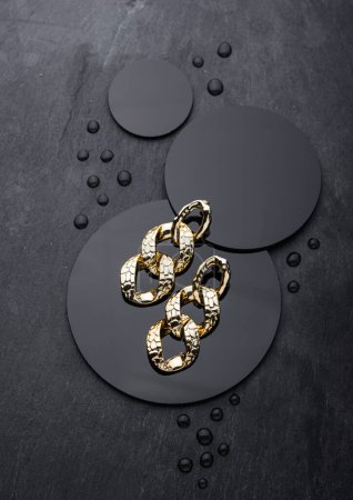 Téléchargez les photos : Boucles d'oreilles chaînes dorées sur fond noir. Bijoux concept de photographie - en image libre de droit