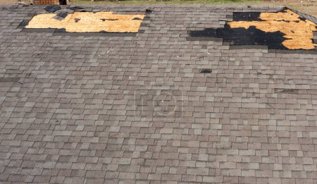 Roof with missing shingles, damaged by tornado during severe weather