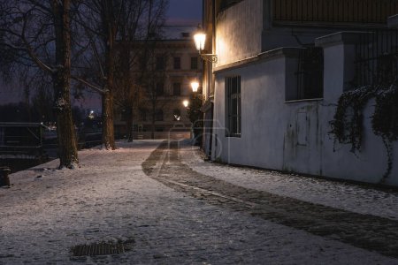 Calles nevadas de Praga con luces de calle iluminadas por la noche