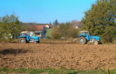 Téléchargez les photos : Deux tracteurs bleus sur un champ. - en image libre de droit