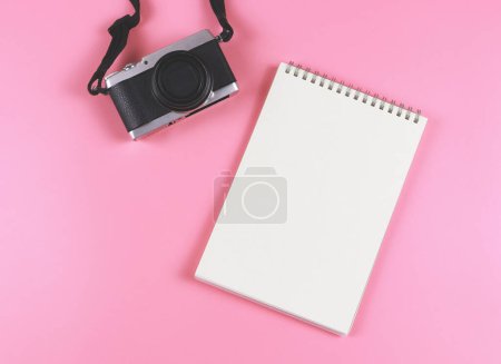 Foto de Top view or flat lay of blank page opened notebook and camera on pink background. - Imagen libre de derechos