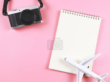 Foto de Vista superior o plano disposición de la página en blanco abrió portátil, modelo de avión y cámara en fondo rosa con espacio de copia. - Imagen libre de derechos