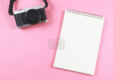 Foto de Vista superior o disposición plana de la página en blanco abrió el cuaderno y la cámara en el fondo rosa con espacio de copia. - Imagen libre de derechos