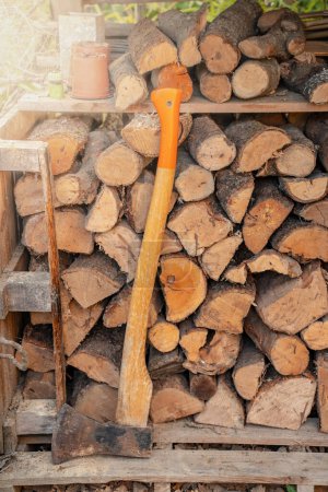 Téléchargez les photos : Hache devant une pile de bois dans un hangar à bois. Contexte naturel. Photo de haute qualité - en image libre de droit