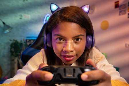 Glückliche lateinamerikanische Spielerin, die mit Mikrofon und Kopfhörern mit Bleiohren ein Videospiel online streamt. Hochwertiges Foto