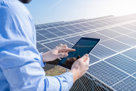 Foto de Ingeniero con una tableta con planta de sistema de panel solar fotovoltaico en el fondo. Concepto de energía limpia verde. - Imagen libre de derechos