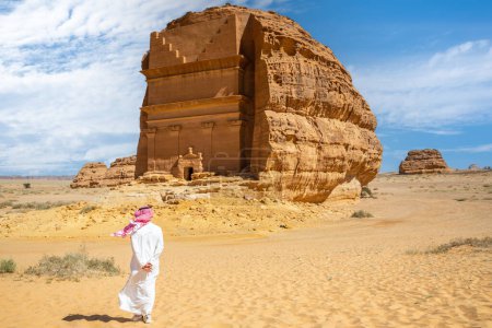 Téléchargez les photos : Homme arabe devant la tombe de Lihyan, fils de Kuza sculpté dans la roche dans le désert, Maca'in Salih, Hegra, Arabie Saoudite - en image libre de droit