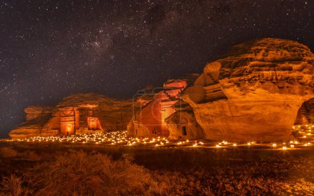 Foto de Cielo estrellado sobre las antiguas tumbas nabateas de la ciudad de Hegra iluminadas, panorama nocturno, Al Ula, Arabia Saudita - Imagen libre de derechos