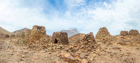 Grupo de antiguas tumbas colmena de piedra con la montaña Jebel Misht en el fondo, sitio arqueológico cerca de al-Ayn, sultanato de Omán