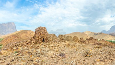 Groupe d'anciennes tombes de ruches en pierre avec la montagne Jebel Misht en arrière-plan, site archéologique près d'al-Ayn, sultanat d'Oman