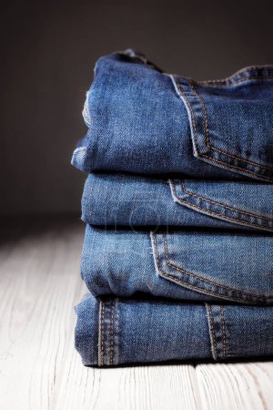 Photo for Worn denim trousers. Machine stitch close up. Denim texture in blue. The concept of repairing old clothes. Sewing factory. Fashionable aging clothes. Stack of jeans. - Royalty Free Image