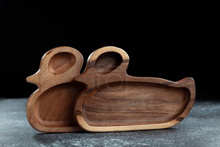 Photo for The children's plate in the shape of a duck is made of wood for serving snacks, fruits, nuts, cheeses, meat and original serving of main dishes. Accessories for a modern kitchen. - Royalty Free Image