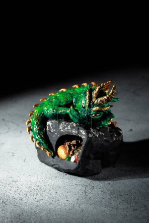 Foto de Un dragón verde con espigas doradas sentado en una gran piedra. Figura del símbolo de 2024. Fondo oscuro con espacio para una inscripción. Tarjeta de invitación para Año Nuevo Chino. - Imagen libre de derechos