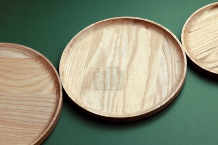Photo for Wooden flat plates on a green background. The concept of ecological tableware. Products for modern kitchen. Zero emissions. - Royalty Free Image