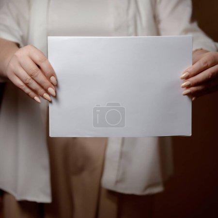 Creative start: a blank piece of paper waiting for inspiration. White sheet of paper in female hands. Place for an inscription on a psychological theme. White sheet of paper in female hands.
