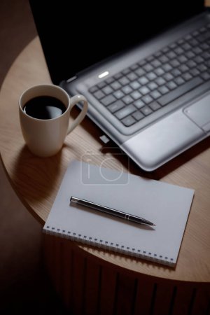 Schreibtischhoch: Laptop, leere Seite und aromatischer Kaffee. Kaffee kreativ: Ideen auf einem weißen Blatt mit einem Kaffeegetränk. Business in allen Schattierungen: Professionelle Eleganz in jedem Rahmen.