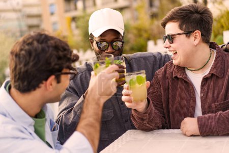 Photo for Happy positive friends cheering mojito drinks at cocktail bar pub outdoor - Multi-ethnic positive young people having fun drinking cocktails on happy hour at pub - Party time and youth culture concept - Royalty Free Image