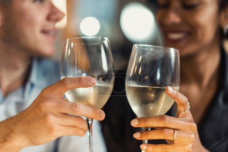 Téléchargez les photos : Couple Interracial sur la date au restaurant souriant et cliquetis vin blanc - homme et femme multiraciale s'amuser à boire et à dîner ensemble - en image libre de droit