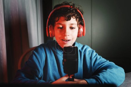Foto de Little vlogger wannabe - kid in his room talking on the microphone and recording his social video - technology and people lifestyle concept - Imagen libre de derechos