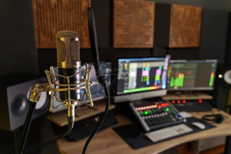 Microphone professionnel dans un petit poste de travail de studio de production sonore - équipement numérique dans la salle de production, avec mélangeur, ordinateurs et haut-parleurs