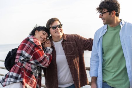 Foto de Group of four friends having fun together. Two women and one men talking laughing and enjoying their time seaside - different people lifestyle concept - Imagen libre de derechos