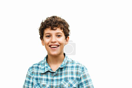 Téléchargez les photos : A 10-year-old boy wearing a checkered shirt, with a big smile on his face, looking directly at the camera. He is isolated from the background and captured in a shoulder-up shot. - en image libre de droit