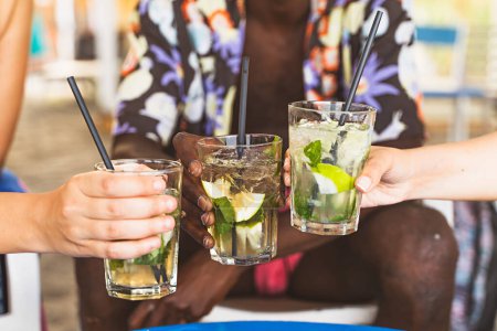 Téléchargez les photos : Close-up of toasting mojito cocktails on the beach bar - en image libre de droit
