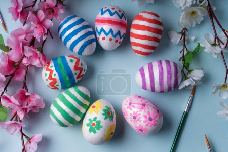 Téléchargez les photos : Vibrant and cheerful flat lay background features circle of colorful Easter eggs adorned with festive decorations, surrounded by spring blossoms and brushes. For website, social media, greeting cards - en image libre de droit