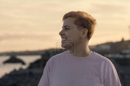 Photo for A radiant non-binary individual, showcasing a joyful smile. Their short-dyed hair further emphasizes their vibrant personality in this close-up portrait. - Royalty Free Image