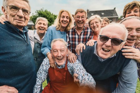 Téléchargez les photos : Un groupe vivant de personnes âgées sont prises dans un moment franc de joie et de rire pur. Réunis à l'extérieur, leurs sourires authentiques et leur lien étroit rayonnent de chaleur et de beauté d'une amitié durable.. - en image libre de droit