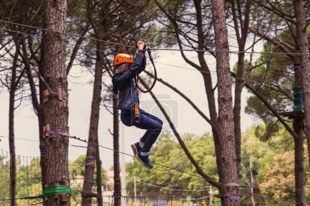 Téléchargez les photos : Une tyrolienne aventurière avec vitesse parmi les grands pins, profitant d'une activité de plein air exaltante. - en image libre de droit