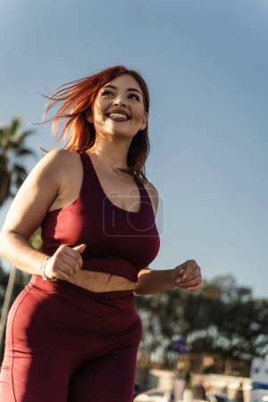 Photo for A vibrant woman enjoys a running session on a city park, showcasing her fitness routine and the energy of an active lifestyle - Royalty Free Image