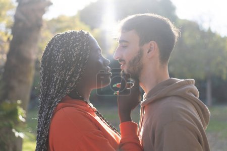 Foto de Un joven y una mujer comparten un momento tierno con el resplandor dorado de la puesta de sol detrás de ellos, lo que insinúa romance - Imagen libre de derechos