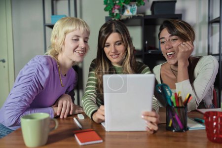 Foto de Tres mujeres jóvenes comparten ideas en un entorno de oficina colaborativa, destacando el trabajo en equipo y la diversidad. - Imagen libre de derechos