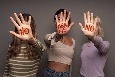 Téléchargez les photos : Trois femmes affichent hardiment "NON signifie NON" écrit sur leurs paumes, symbolisant le consentement et l'autonomisation - en image libre de droit