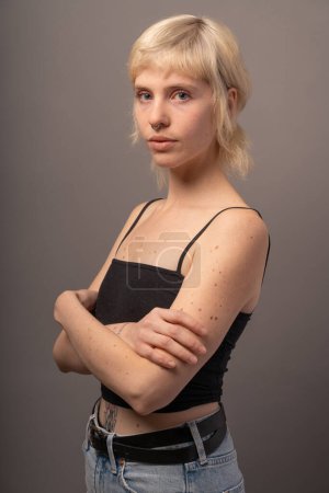 Photo for Portrait of a confident young woman with a septum piercing, showcasing an edgy style with a casual tank top and denim jeans. Her candid expression and minimalistic attire capture a modern aesthetic - Royalty Free Image