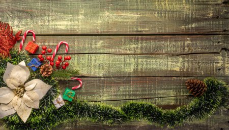 Foto de Decoraciones navideñas variadas que incluyen una corona festiva, conos de pino y bastones de caramelo en una superficie de madera envejecida.. - Imagen libre de derechos