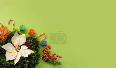 Foto de Un vibrante telón de fondo verde destaca una corona de Navidad decorativa adornada con bastones de caramelo, regalos y conos de pino - Imagen libre de derechos