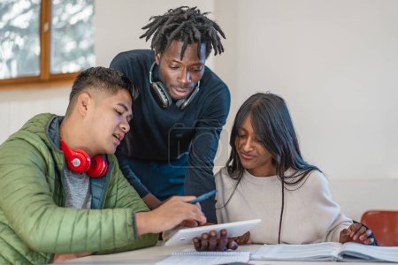 Drei multikulturelle Studenten nehmen an einer interaktiven Lerneinheit mit Notizen und digitalen Geräten teil und teilen ihr Wissen.