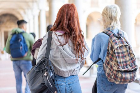 Foto de Estudiantes con mochilas pasean por los históricos salones universitarios, inmersos en la vida del campus. - Imagen libre de derechos