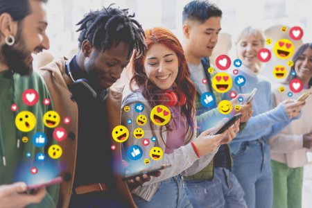 Téléchargez les photos : Les jeunes adultes excités partagent et réagissent au contenu sur les médias sociaux, entourés d'une foule d'émoticônes colorés dans une scène vibrante. - en image libre de droit