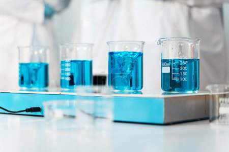 Téléchargez les photos : Béchers remplis de liquide bleu sur un banc de laboratoire, mettant en évidence la mesure et l'analyse scientifiques. - en image libre de droit
