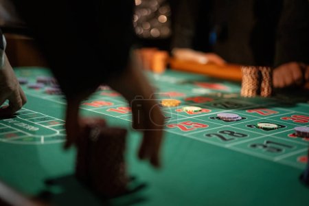 Téléchargez les photos : Gros plan dramatique des mains plaçant des paris sur une table de roulette, capturant le frisson du pari. - en image libre de droit